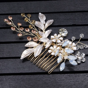 Close-up of golden bridal hair comb with crystals, metallic leaves and white flowers