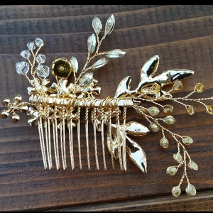 Macro shot of gold bridal hair comb featuring crystal leaf details on dark wood surface