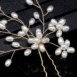 Detail of handcrafted bridal pearl hair pin with gold wire and elegant floral branch design