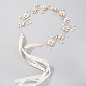 Macro shot of white enamel daisies and faux pearls on a gold-wire bridal headband