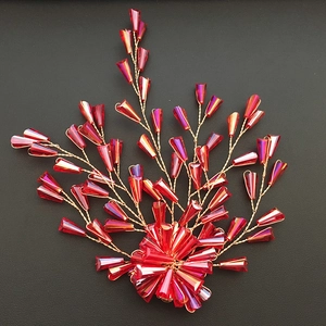 Detailed close-up of handmade red crystal beaded bridal hair clip with gold wire on black leather
