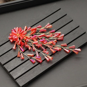 Macro detail of red crystal beads and gold wire craftsmanship on bridal hair clip