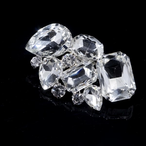 Macro shot of silver crystal shoe clips with pear and oval rhinestones on black background
