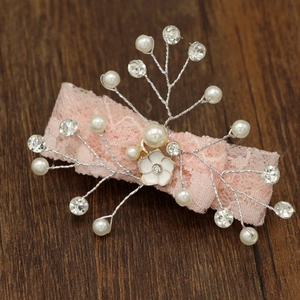 Dettaglio del fermaglio per capelli in pizzo rosa con perle sintetiche e strass chiari