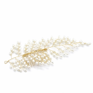 Close-up detail of golden bridal hair comb with handmade pearls and wire leaves