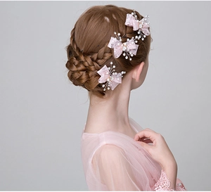 Dettaglio del fermaglio a fiocco in pizzo rosa con perle e strass su capelli intrecciati