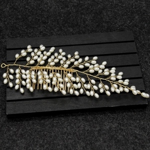 Detail of handcrafted gold wire bridal hair comb with elegant white faux pearl leaves
