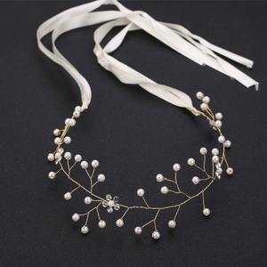 Dettaglio di un tralcio per capelli dorato con perle e strass su sfondo scuro elegante