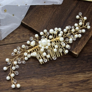 Close-up of handmade bridal hair comb with gold wires, white pearls and crystal beads