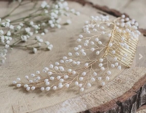 Close-up of handmade gold wire hair comb with pearls on rustic wood stump background