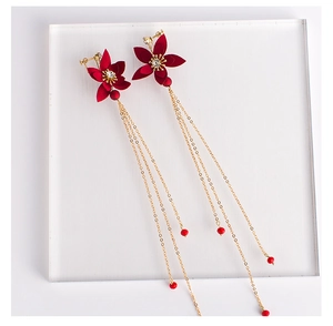Détail de boucles d'oreilles de mariée fleur rouge avec longs pompons dorés et clips