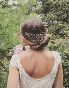 Elegant gold leaf bridal hair comb with pearls styled on a romantic low bun hairstyle