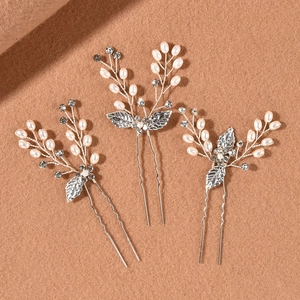 Detail of three silver bridal hair pins with pearls, crystals, and leaf ornaments