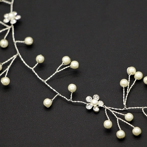 Dettaglio fascia da sposa con fili d'argento, perle bianche e fiori di strass lucidi
