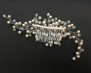 Detail of silver bridal hair comb with handmade pearls and crystal beads on black background