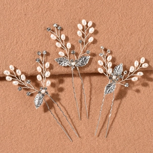 Detailed macro view of bridal hair pins with golden leaves, pearls, and crystals on felt