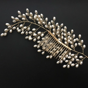 Handmade gold bridal hair comb with elegant pearl leaves on a black textured surface