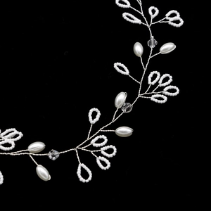 Handmade freshwater pearl bridal hair vine with silver wire leaf design on black background