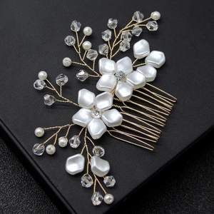 Close-up of bridal hair comb with white shell flowers, pearls and crystals on gold wire