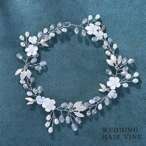 Elegant bridal wedding hair vine with silver leaves, white flowers and pearls on blue fabric