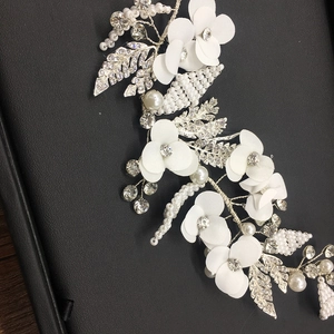 Elegant bridal headpiece with white fabric flowers and shimmering pearl leaf accents