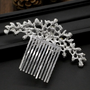 Macro detail of vintage silver bridal hair comb with coral branch design on black leather