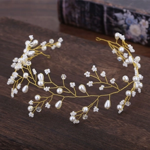 Macro d'un serre-tête en fil doré avec perles blanches et petites fleurs perlées