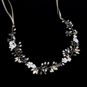 Detail of handmade bridal headband with gold leaves, white flowers and pearls on black back