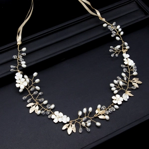 Detailed macro view of golden leaf bridal hairpiece with crystal, pearl and ceramic flowers