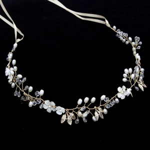 Detail view of bridal headband with gold leaves, pearls, crystals, and white fabric flowers