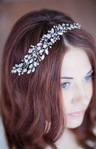 Detailed close-up of bridal crystal hairpiece with leaf design on red-brown hair