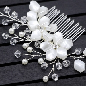 Macro detail of bridal hair comb with white pearl petals and silver wire crystals
