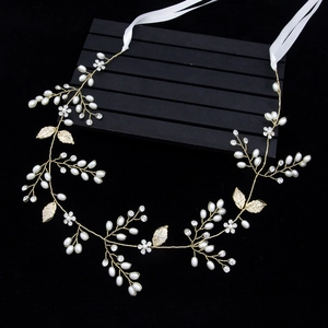 Détail d'un serre-tête de mariée fait main avec feuilles dorées, perles et rubans de soie