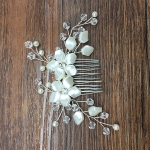 Macro detail of bridal hair comb featuring white pearl flowers and crystal bead sprigs