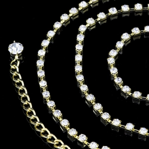 Détail de chaîne de corps dorée ornée de strass avec extension sur fond noir brillant