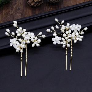 Detail of two handmade bridal hair pins with white pearls, resin flowers, and crystals