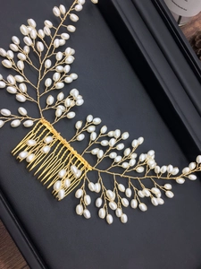 Détail d'un peigne à cheveux de mariée doré avec perles blanches sur fond en cuir noir élégant