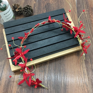 Détail de serre-tête de mariée fait main avec fleurs rouges et fil doré perlé