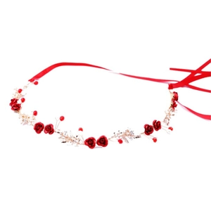 Dettaglio dell'accessorio sposa con rose rosse, foglie dorate e nastro di raso