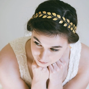 Détail d'un bandeau de mariée doré fait main avec feuilles métalliques sur cheveux sombres