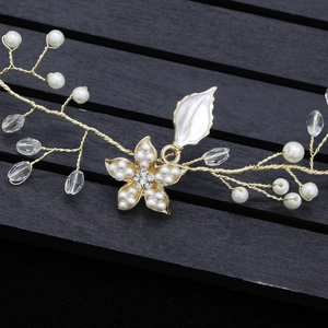 Détail d'un serre-tête de mariée fait main avec fils dorés, perles et fleur en cristal