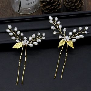 Détail macro d'épingles à cheveux de mariée avec feuilles dorées et perles sur fond noir