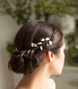 Détail de l'accessoire de cheveux de mariée avec feuilles argentées sur serre-tête vine