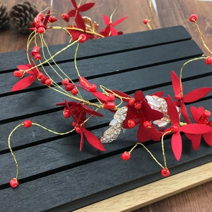 Détails de fleurs en tissu rouge et perles sur un bandeau de mariée fait main