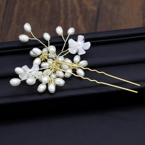 Detail of handmade bridal hair pin with white pearls and resin flowers on gold wire