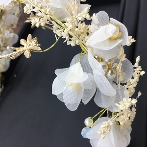 Détails de fleurs en résille pour mariée avec papillon doré et perles sur le serre-tête
