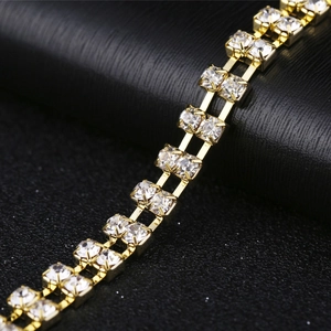 Détail macro d'une chaîne à deux rangées plaquée or avec strass et cristaux
