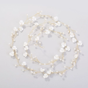 Macro view of bridal hair chain with white pearls and petals on gold wire