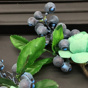 Macro shot of faux blueberries with frost texture and green leaves on black leather