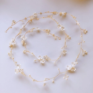 Macro detail of handmade golden hair vine with white flowers and bridal pearls